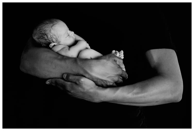 Neugeborenes schläft in den Armen des Vaters.